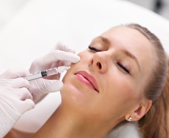 Hands of cosmetologist making botox injection in female lips